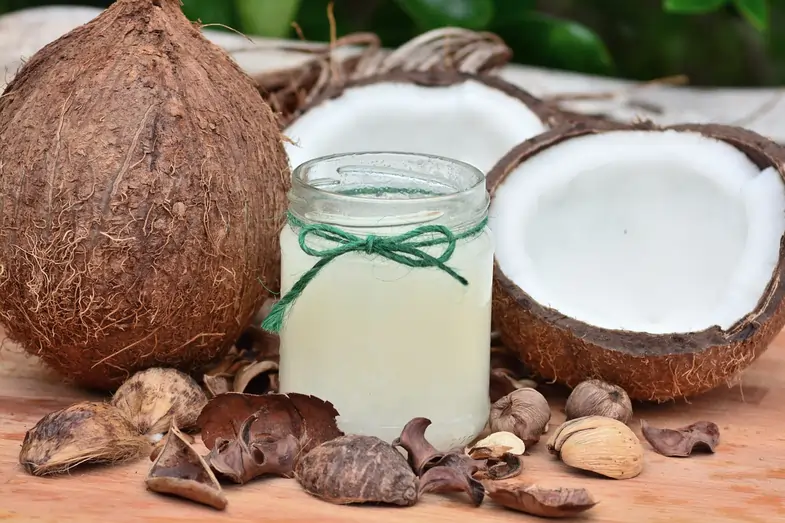 Una nuez de coco con un bote de aceite de coco | Justbob